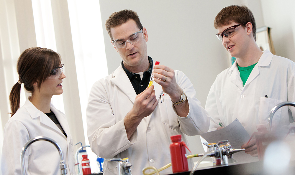 Instructor and students inspect vial