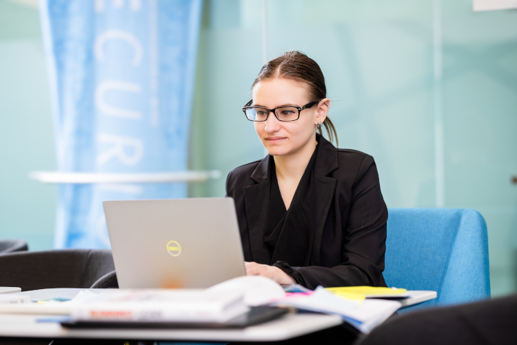 student on a laptop while taking management courses