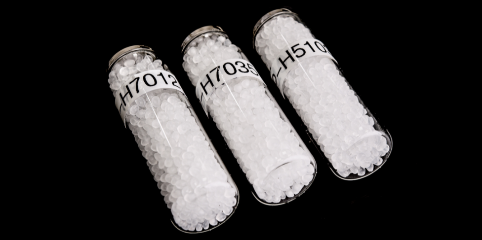 Three small glass bottles filled with small clear/white plastic pellets. The bottles have labels with coded numbers
