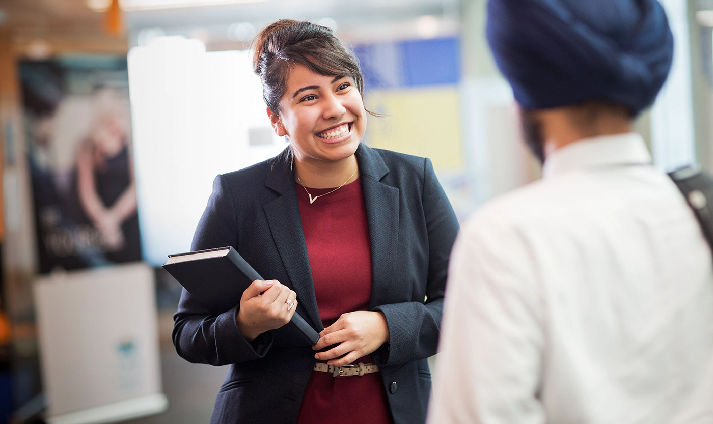 Female employer in suit jacket talking to a student at job fair