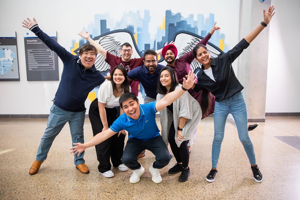 Photo of international students posing in front of a NAIT mural