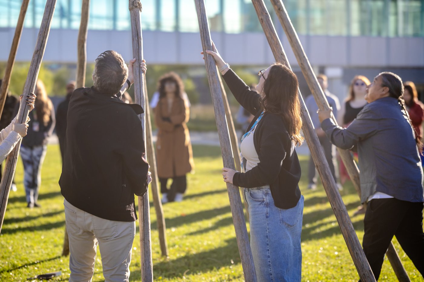 group of students and staff building a tipi