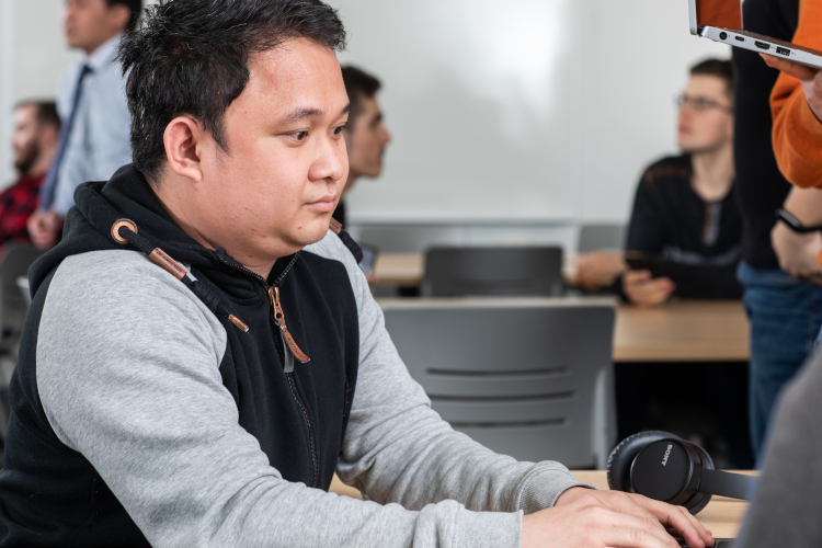 a cybersecurity student working on a computer on the NAIT campus