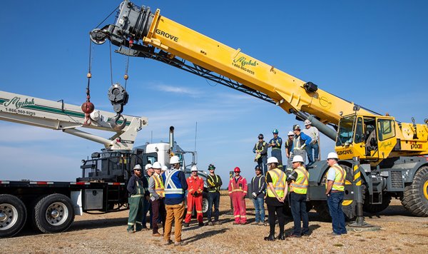 people in protective gear standing in front of cranes