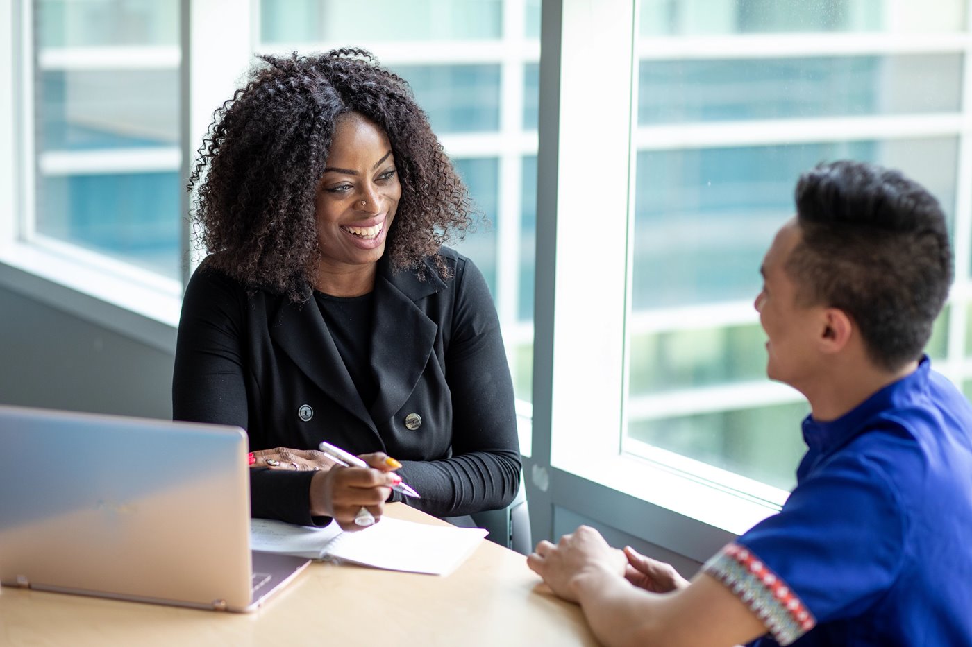 Counsellor speaks to a grad while holding a pen, laptop on table between them