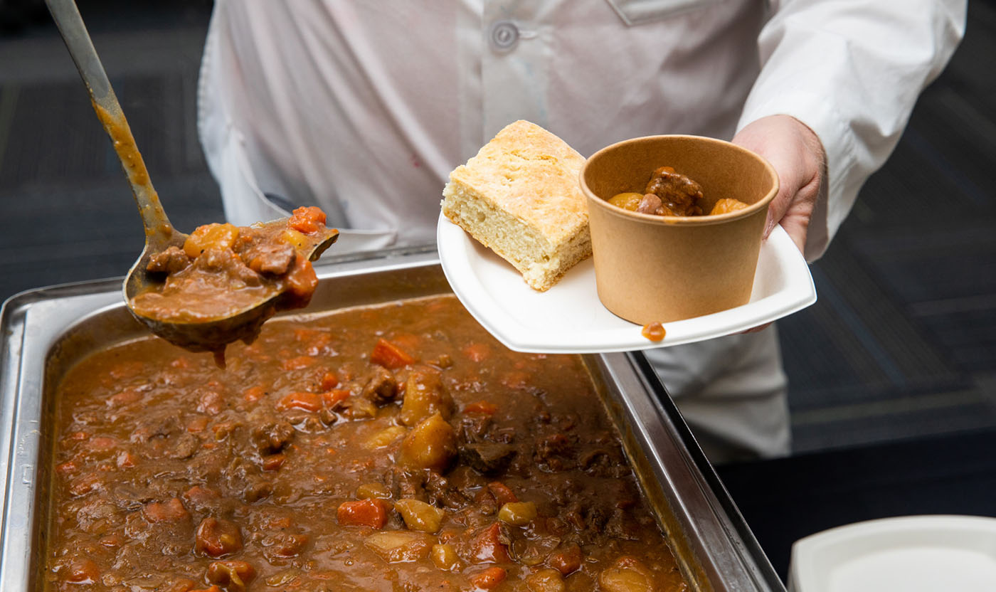 Stew being ladled onto a plate during one of the monthly strew & bannock events.