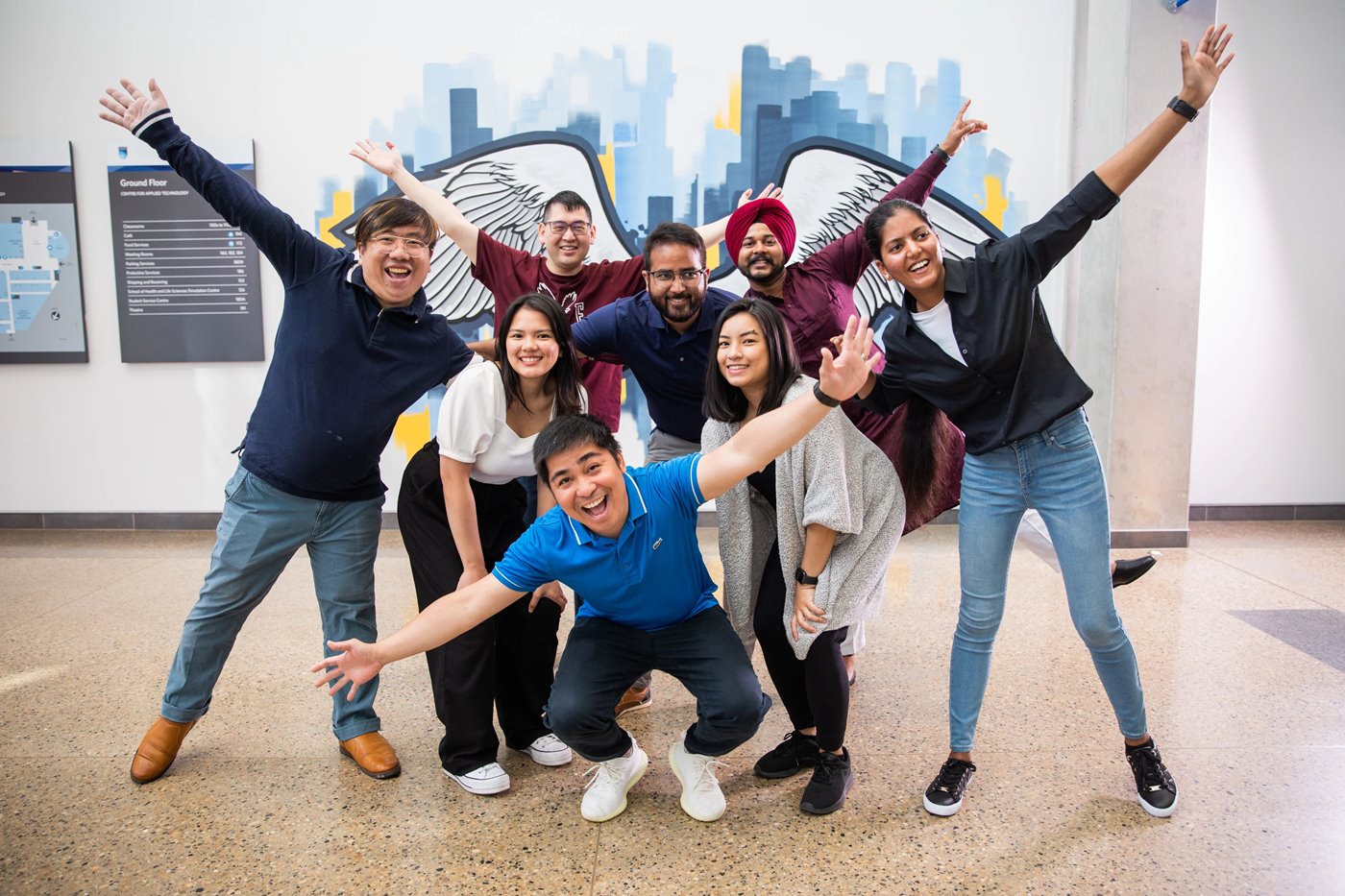 Photo of international students posing in front of a NAIT mural