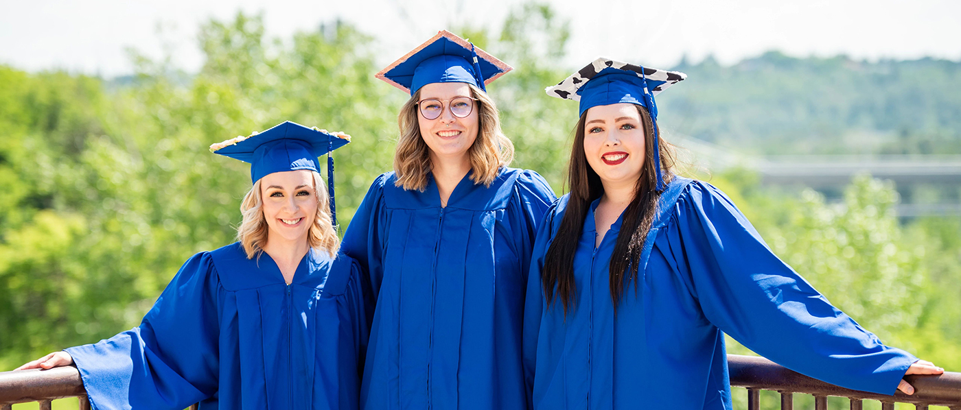 3 female NAIT grads standing outside smiling on convocation day