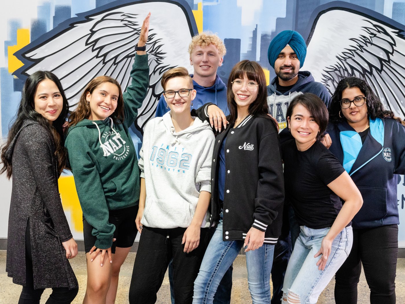 NAIT students pose in front of the Ooks mural
