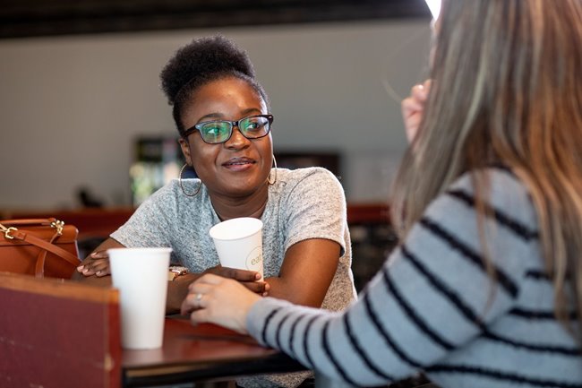 Black woman talking with other woman at table image