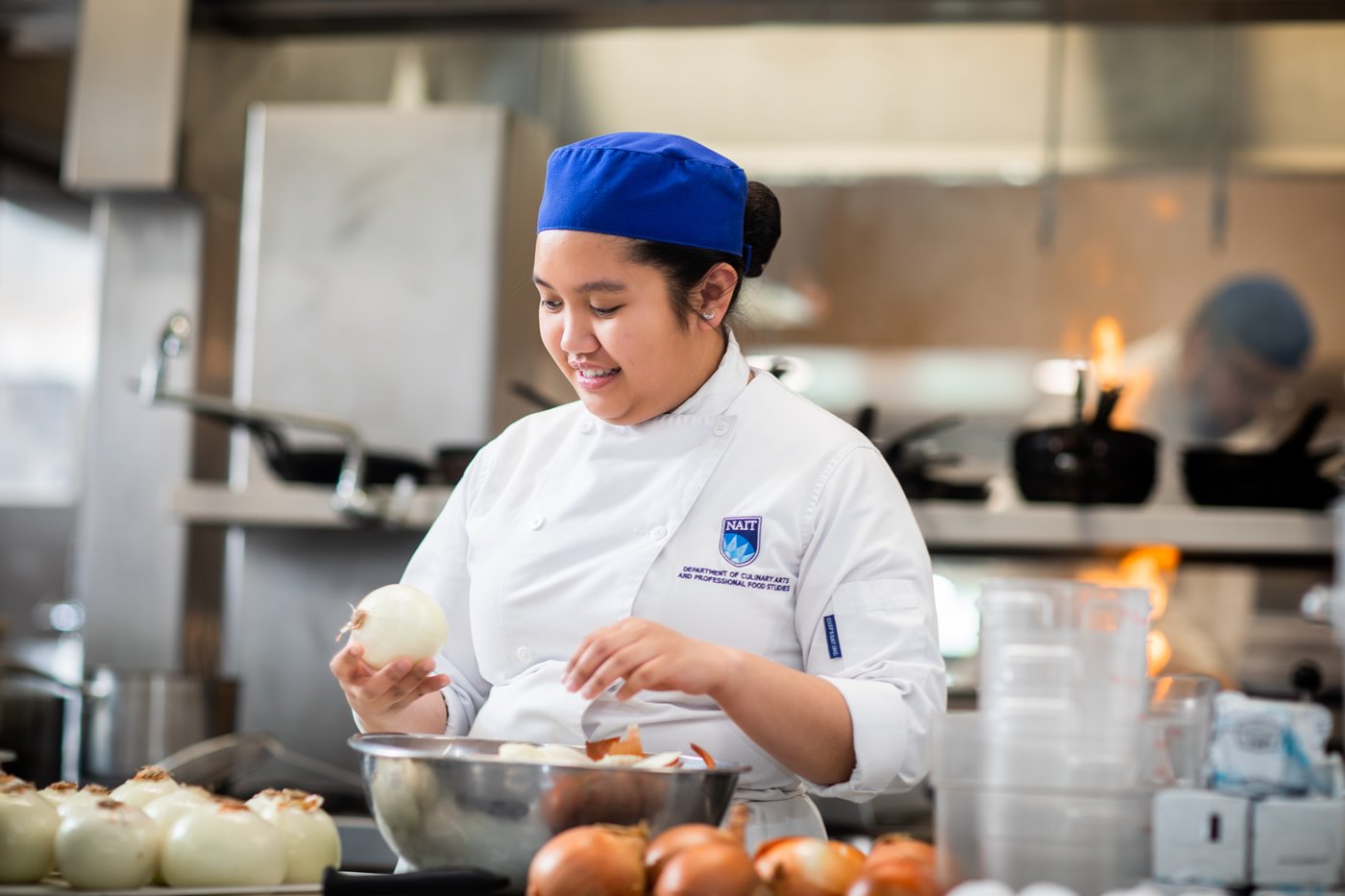 Female culinary student peels onions as mise en place